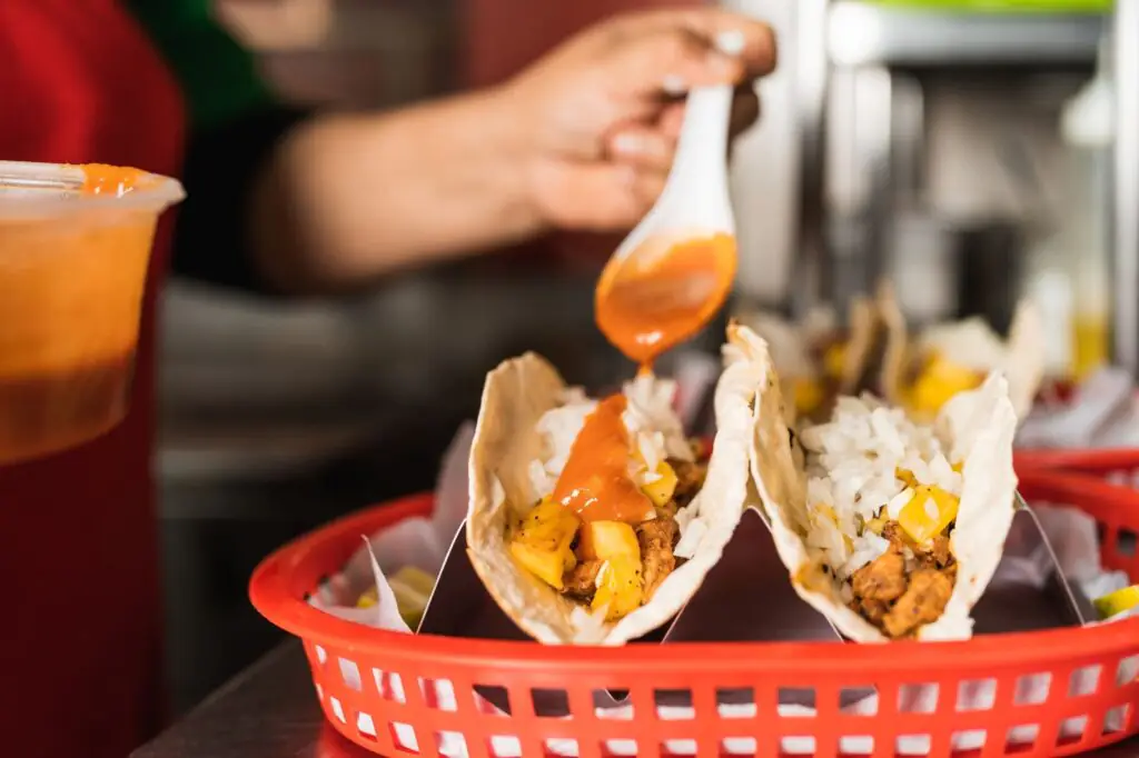 Tacos being sauced in a red basket for Taco Tuesday