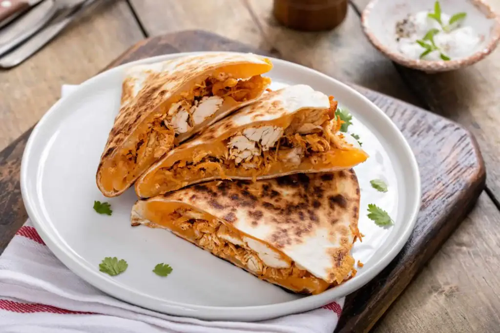 Easy chicken quesadilla wedges with melted cheese on a white plate